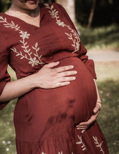 Werdende Mama streicht mit ihrem Händen über ihren Babybauch.