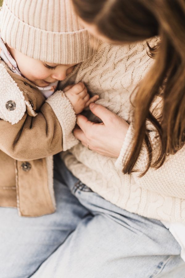 Kleines Mädchen kuschelt sich gemütlich in denn Arm ihrer Mama.