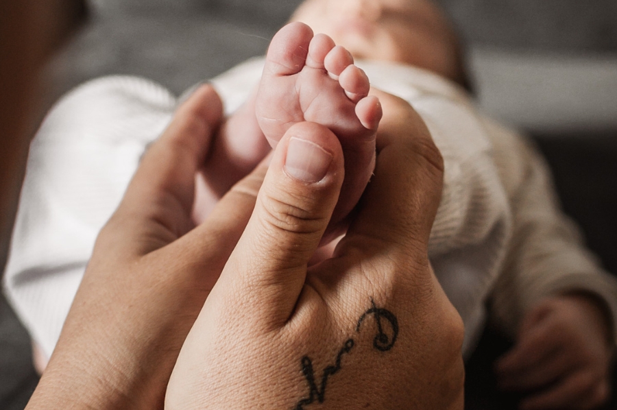 Füße eines neugeborenen Babys in Mamas Händen.