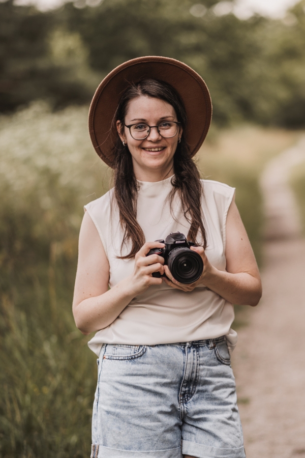 Stefie - Familienfotografin in Nürnberg, Fürth und Umgebung. Auf dem Foto ist die Fotografin mit ihrer Kamera in der Hand zu sehen. Sie lacht freundlich.