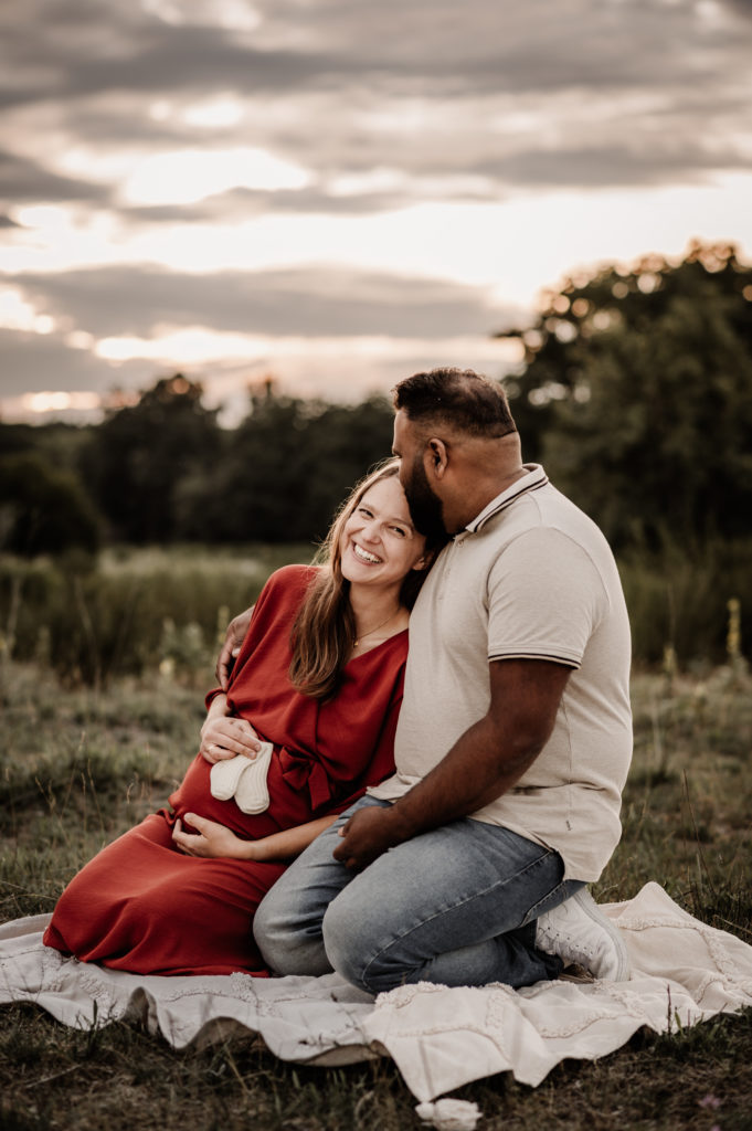 Paar beim Familienfotoshooting in der Natur in Nürnberg. Die freuen sich auf ihr Baby und strahlen miteinander.