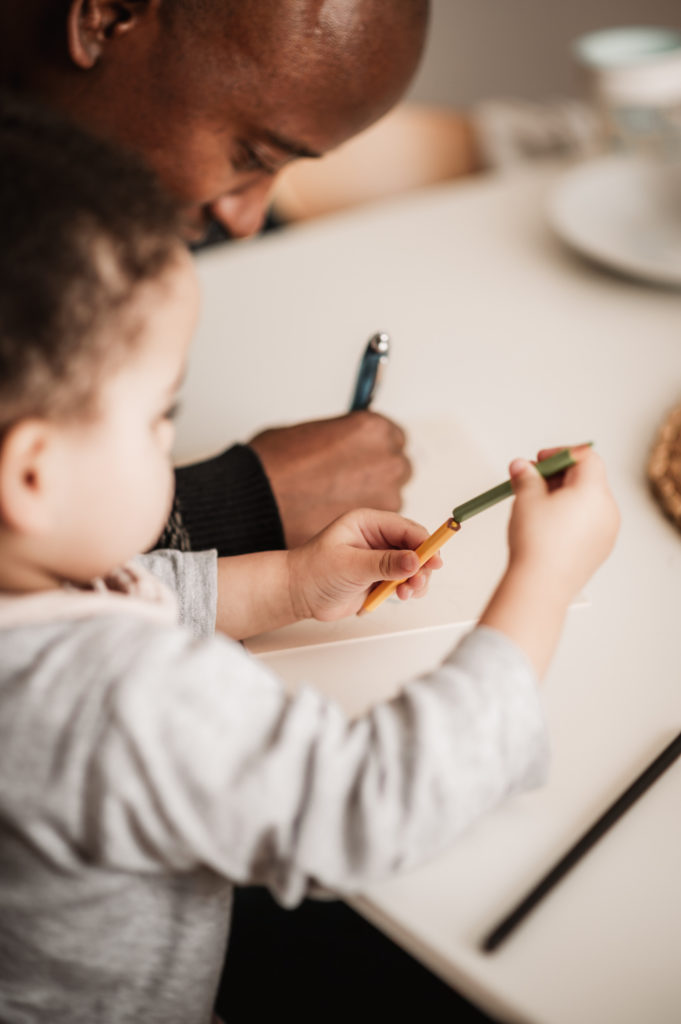 Papa und Tochter am Esstisch machen zusammen eine Karte.