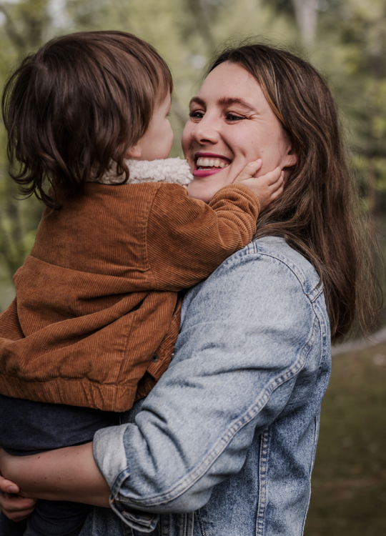 Mama hat ihren Sohn auf den Arm. Sie strahlt. Seine Hand liegt liebevoll auf ihrer Wange. Beide schauen sich an.
