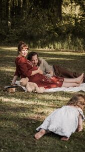 Familie mit werdender Mama und kleinem Kind auf einer Picknickdecke im Park