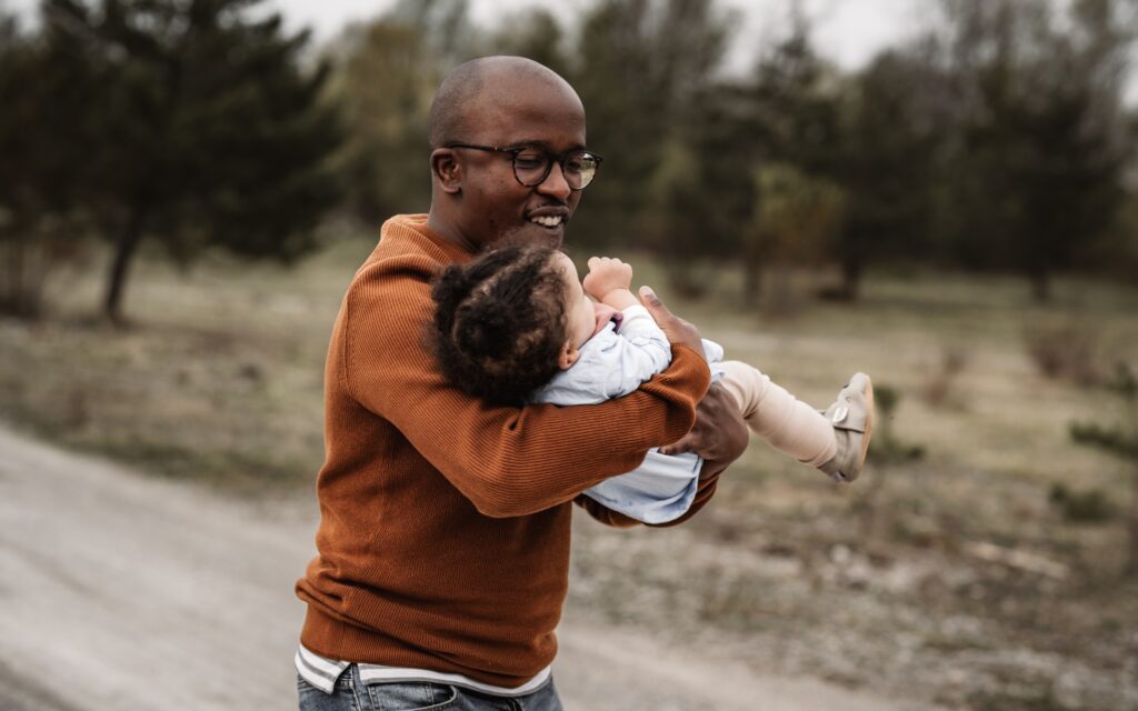 Papa mit kleinem Kind im Arm drehen sich im Kreis und lachen