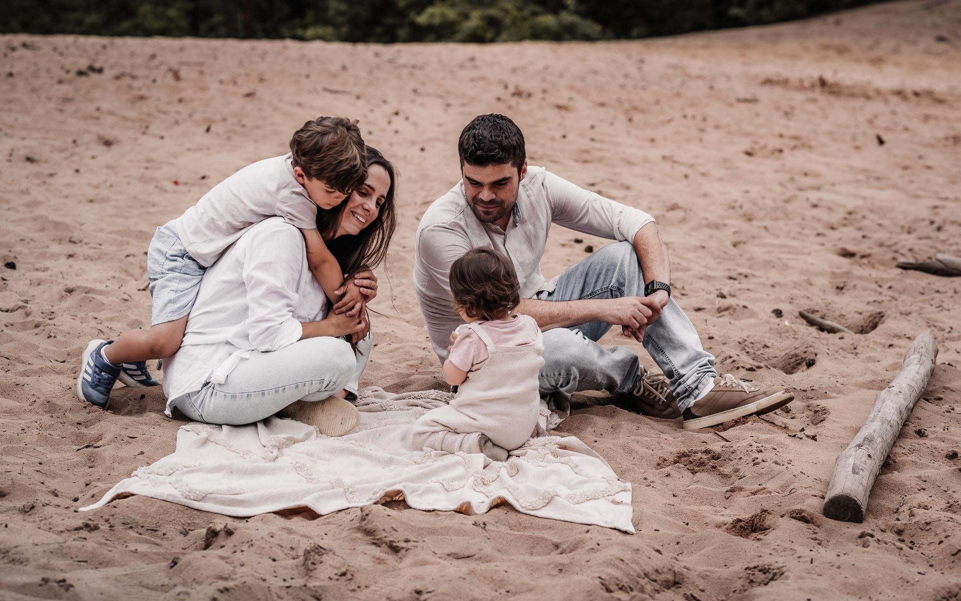 Familie auf einer Sanddüne in Nürnberg beim Familienfotoshooting. Mama und Papa mit zwei kleinen Kindern.