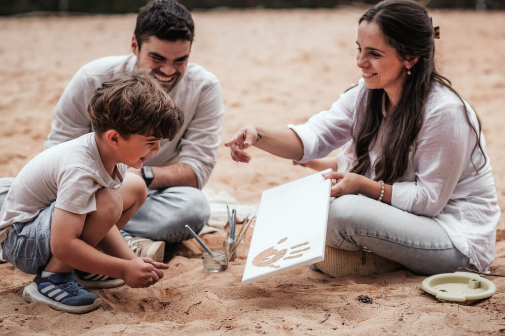Familien beim lustigen Fotoshooting macht Sandbilder mit ihren Handabdrücken