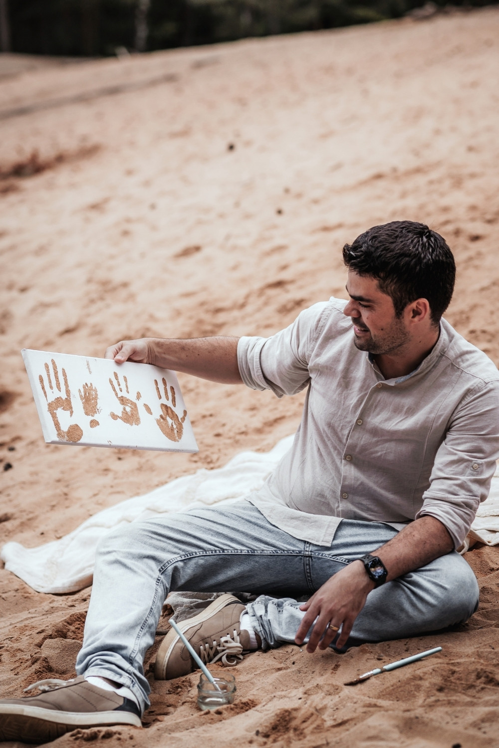 Papa mit einem einer Leinwand mit den Sand-Fingerabdrücken der Familie