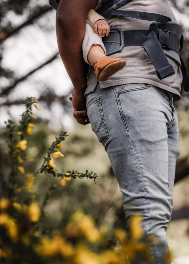 Nahaufnahme von Hand und Fuß eines kleinen Kinder in der Rückentrage