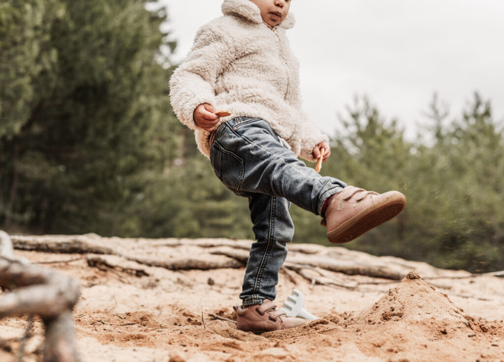 Kleines Kind kcikt mit dem Fuß den Sand auf dem Dünenweg bei Nürnberg. Ihr Gesicht ist nicht sichtbar.