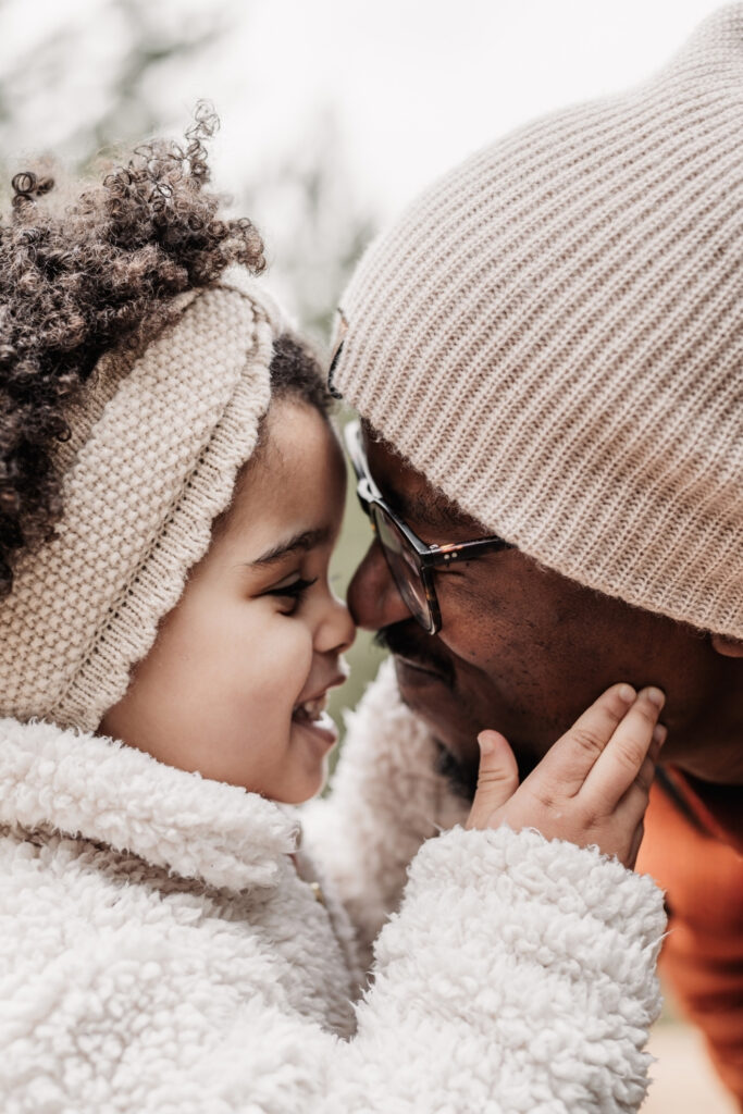Mädchen mit Afrolocken gibt ihrem Papa einen Nasenstubser