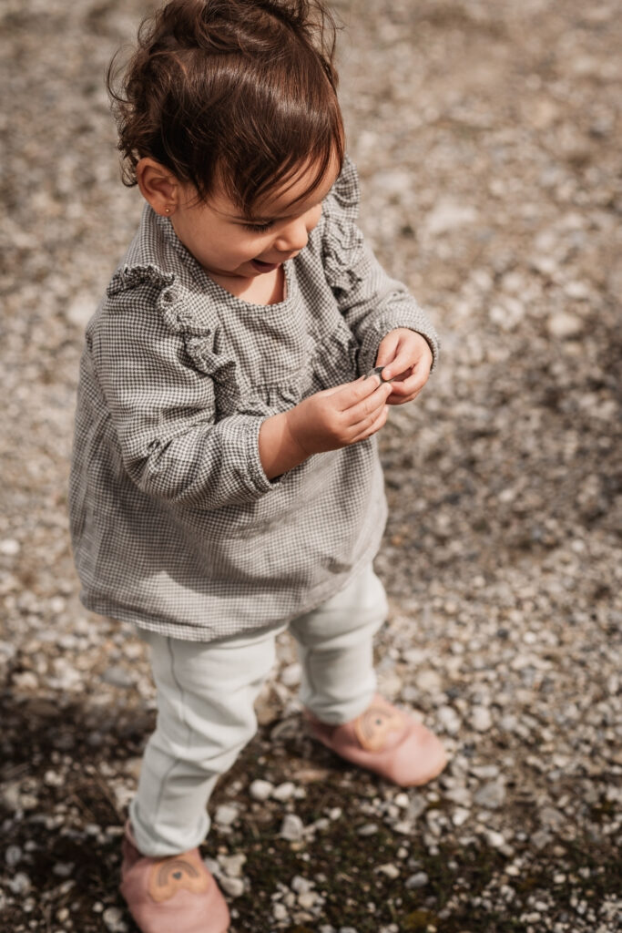Kleines Kind hebt Kieselsteine auf und freut sich